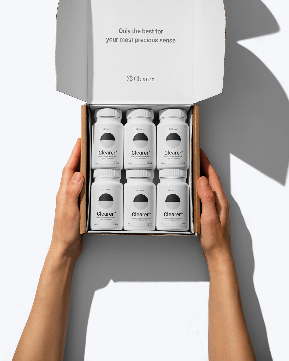 Hands holding an open Clearer box containing six bottles